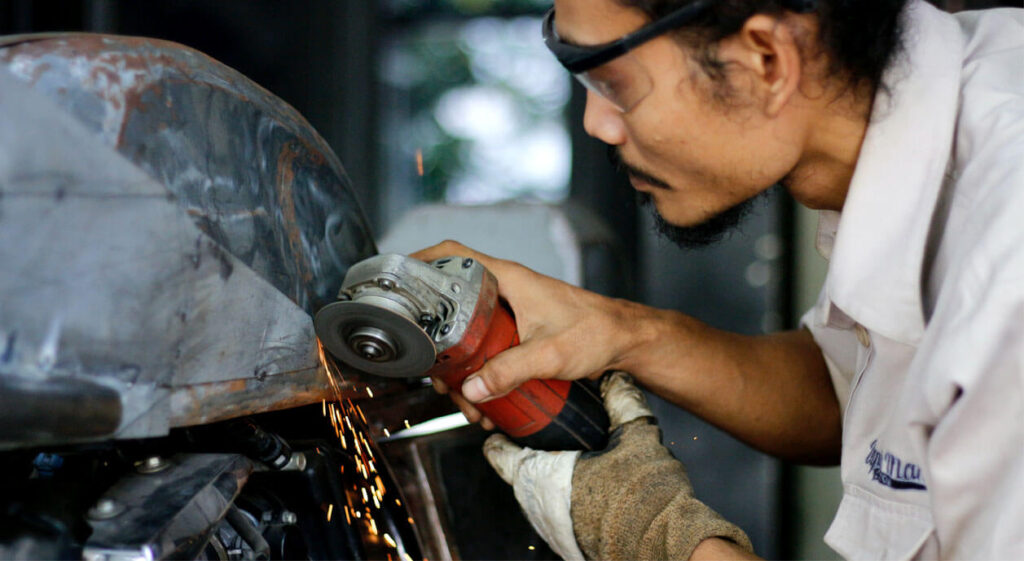 Men performing metal cutting and welding with sparks.
